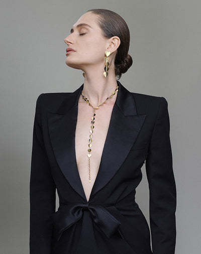 Woman in a black blazer with yellow gold heart necklace and yellow gold heart earrings